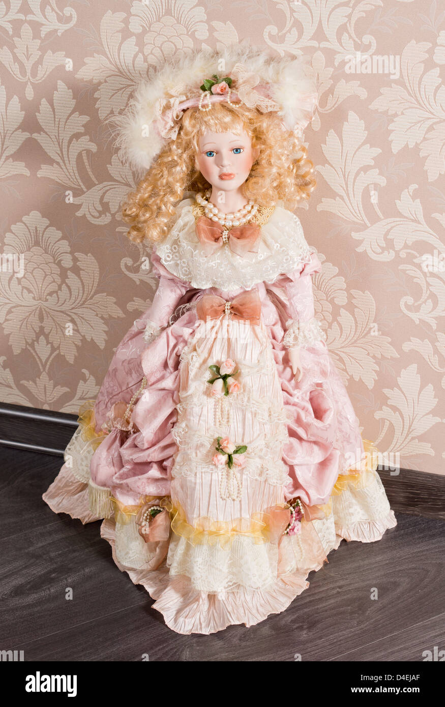 Pretty delicate antique doll with long blonde ringlets dressed in a beautiful pink nineteenth century gown and accessories Stock Photo