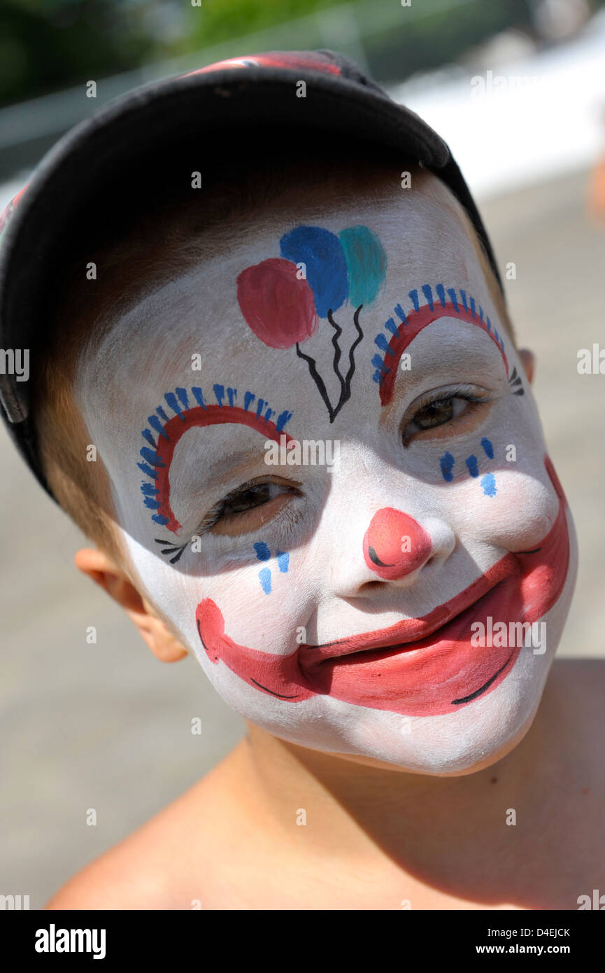 young man named Jackson at the Rotary Splash Pad in Brockville, with his face painted like a clown with balloons Stock Photo
