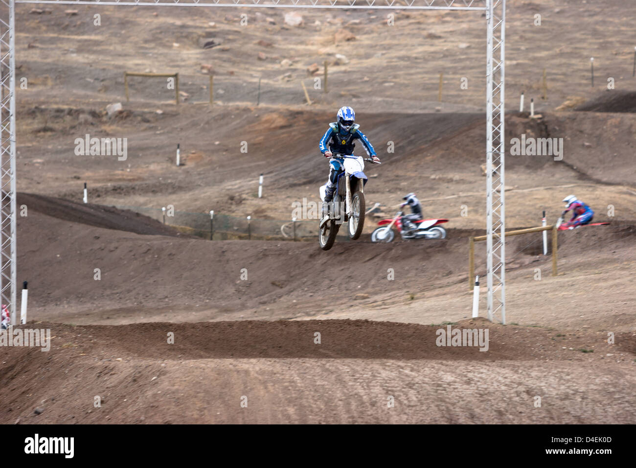 A motorcycle rider jumps through the finish line at an off road