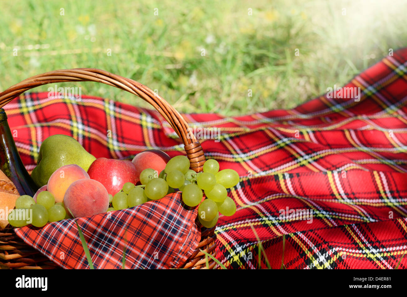 Picnic basket with red napkin fool of fruits, bread and wine Stock Photo