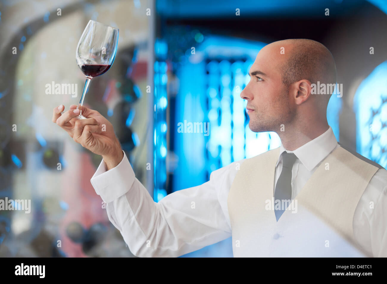Waiter examining glass of wine in restaurant Stock Photo