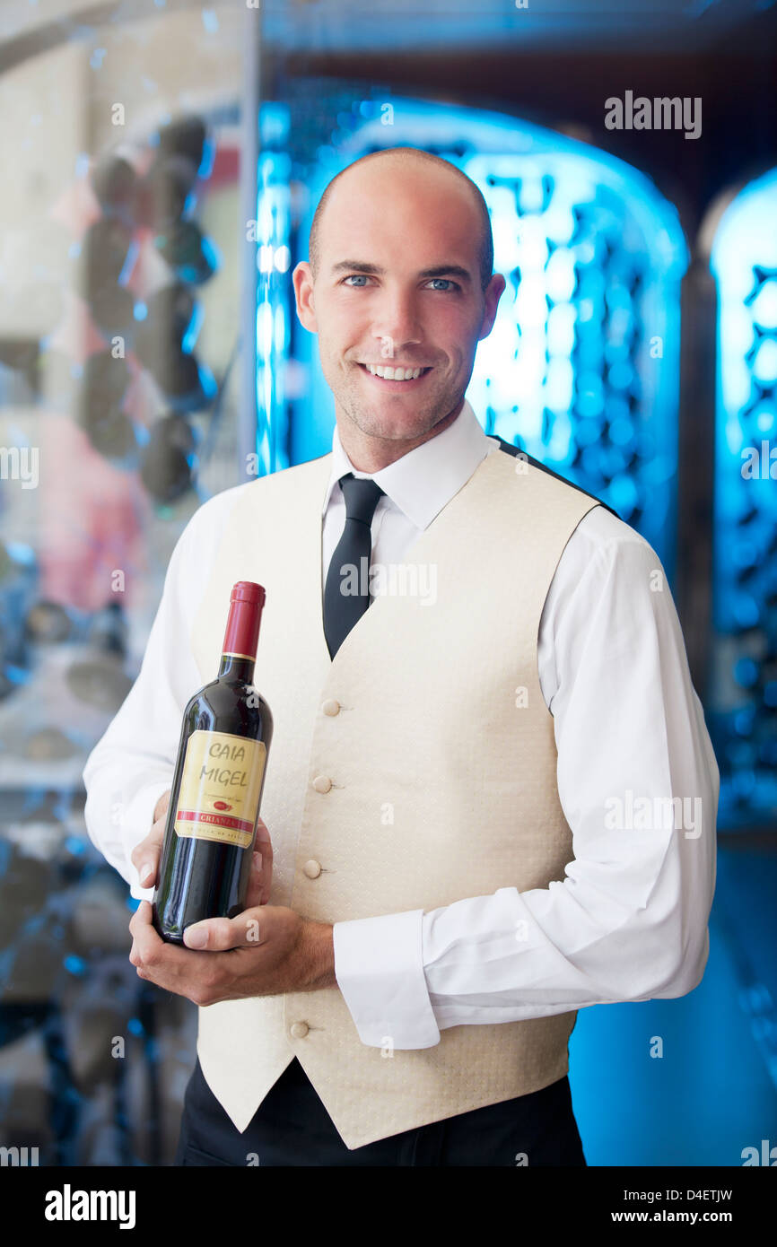 Waiter holding bottle of wine in restaurant Stock Photo