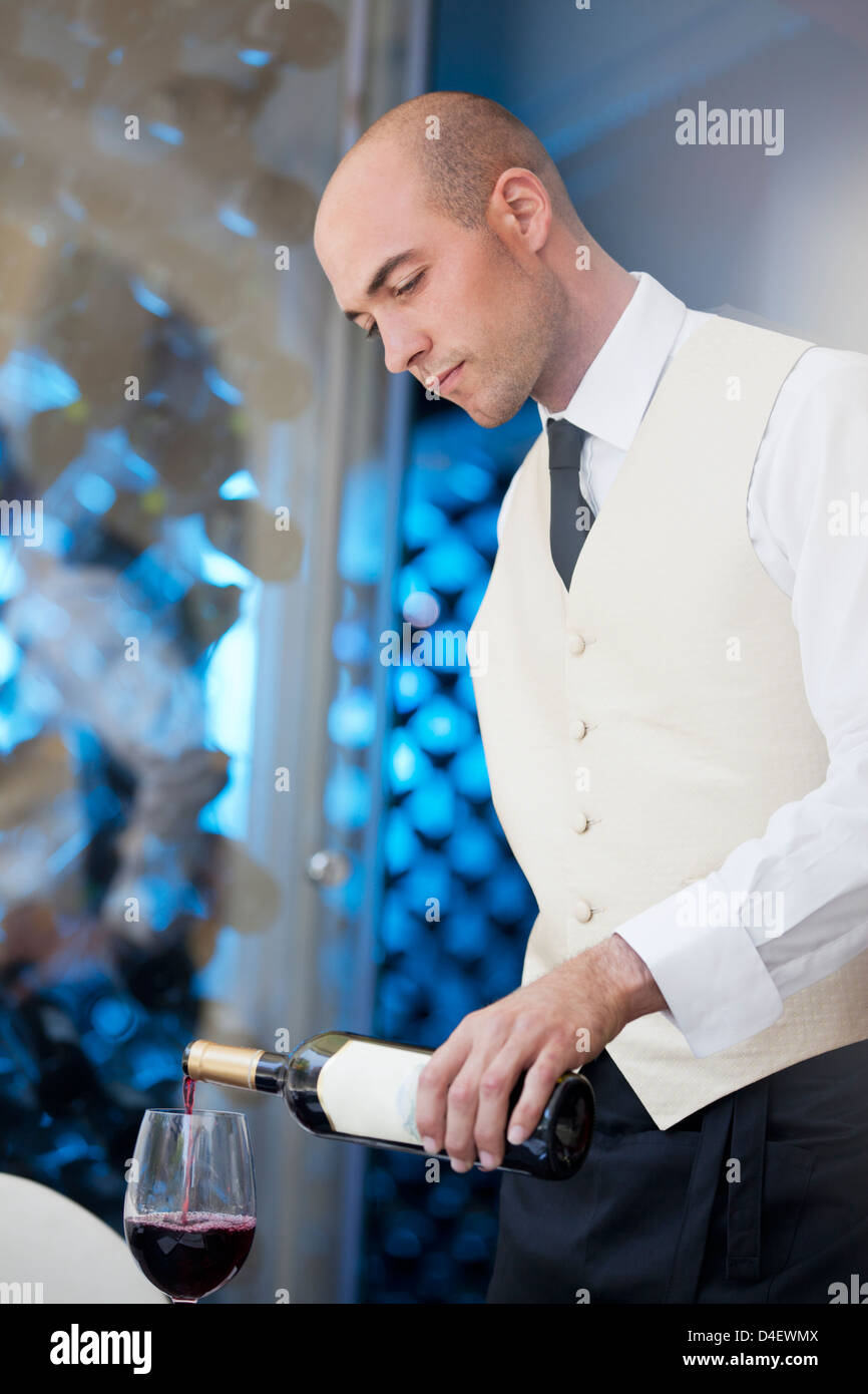Waiter pouring glass of wine in restaurant Stock Photo
