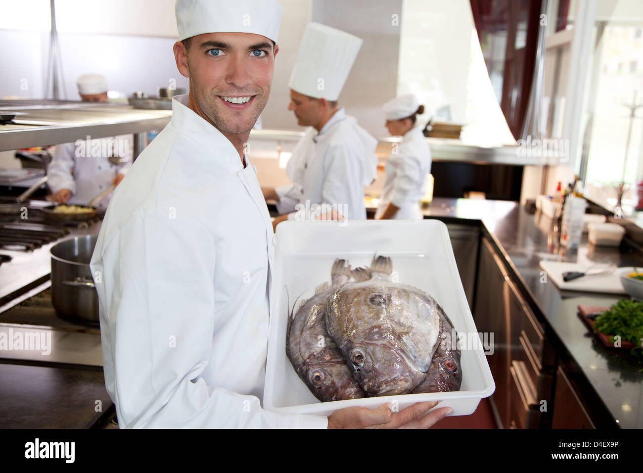 Chef carrying tub of fresh fish in restaurant kitchen Stock Photo