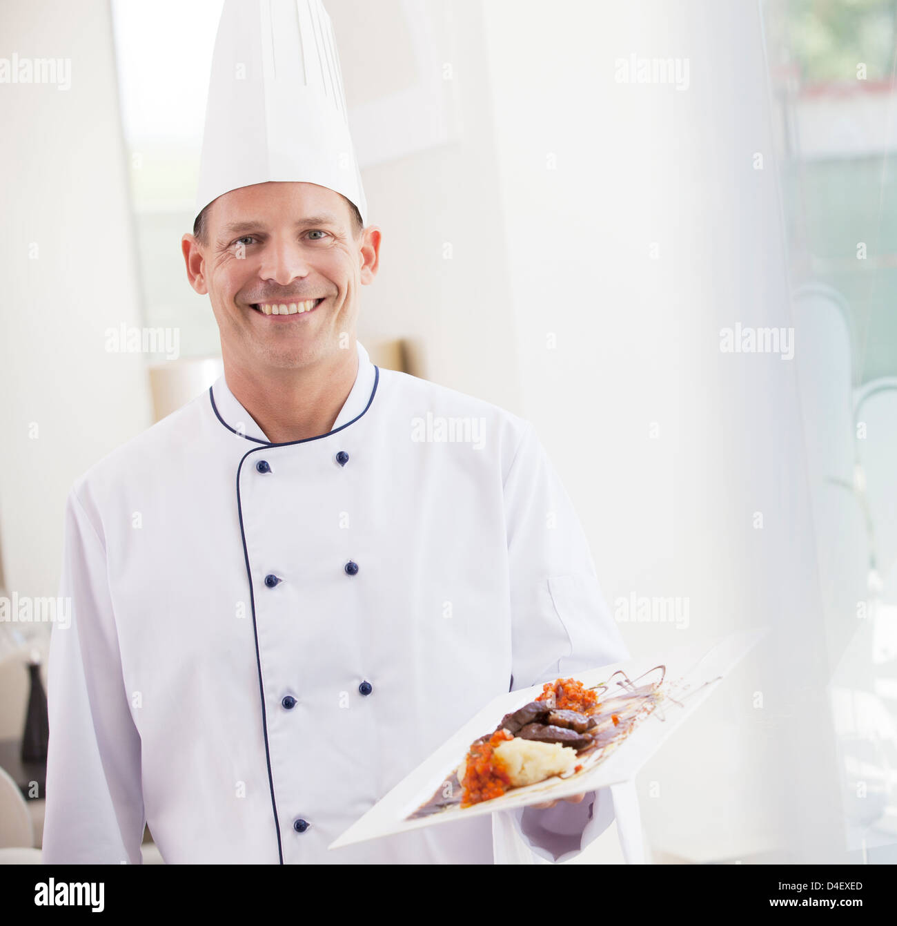 Chef carrying plate of food in restaurant Stock Photo