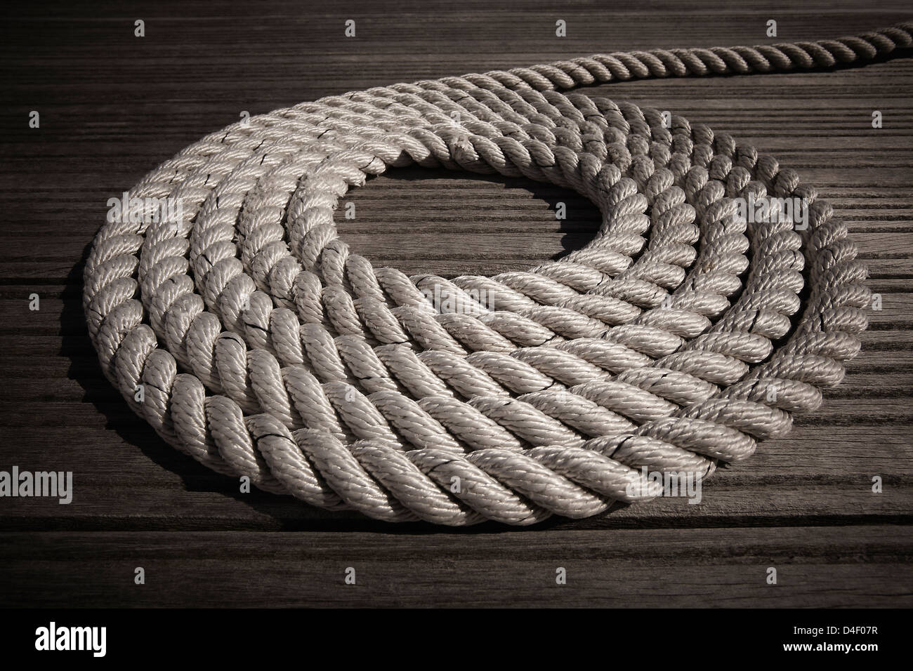 Rope coiled in circle on boardwalk Stock Photo
