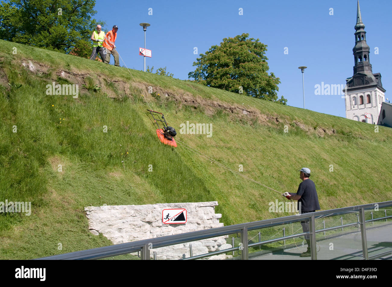 Council gardeners mowing a steep slope by attaching a Flymo with a rope near Freedom Square in Tallinn Old Town, Tallinn, Estonia Stock Photo