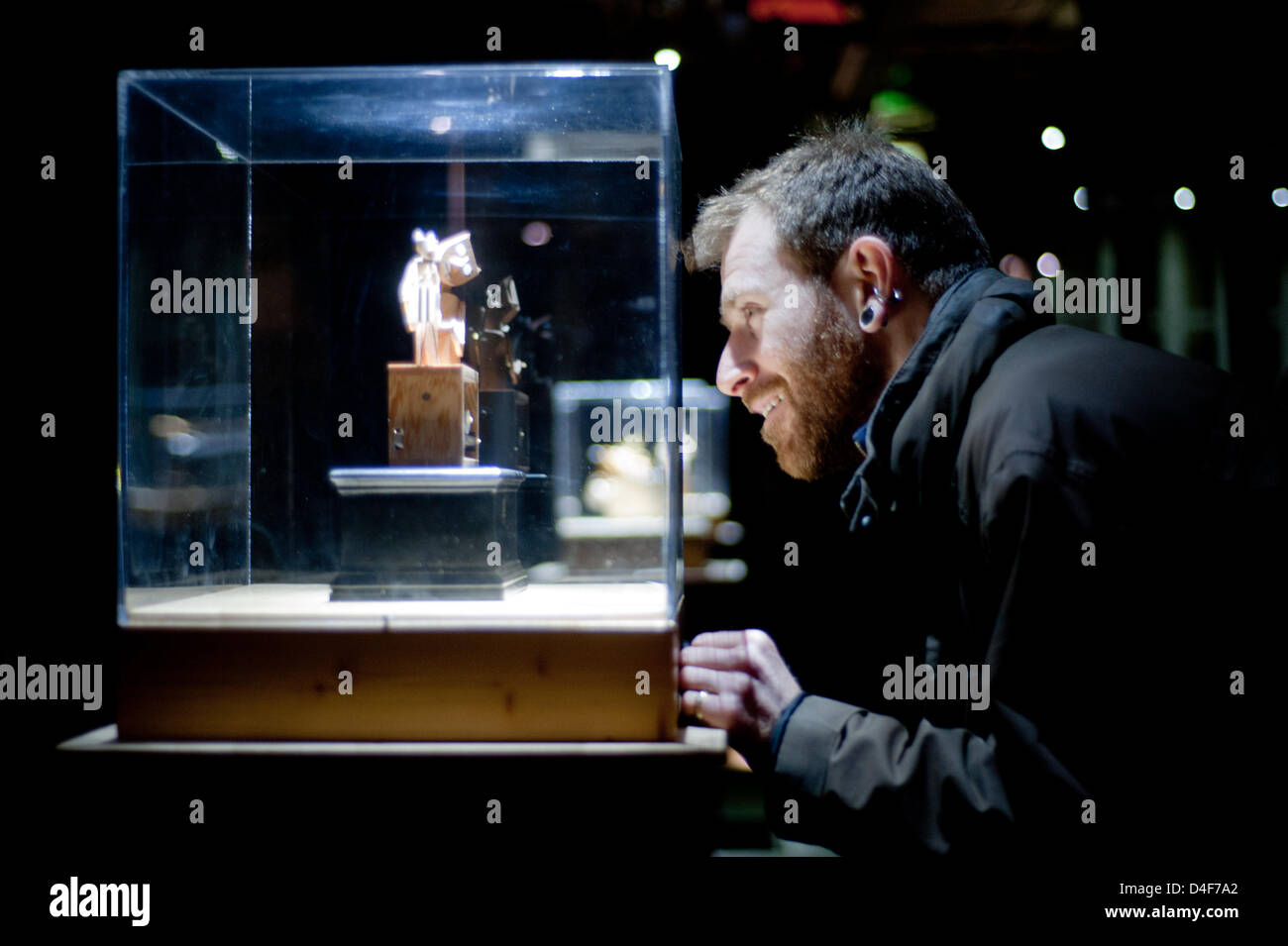 London, UK. 12th March 2013. a visitor looks at The Barecats automata by Paul Spooner at the Cabaret Mechanical Theatre exhibition that opens today aboard MS Stubnitz in Wood Wharf and runs until the 12th of April. The exhibition offers the opportunity to visitors to press the buttons bringing to life these contemporary automata and triggering the small machines into action.  Credit:  pcruciatti / Alamy Live News Stock Photo