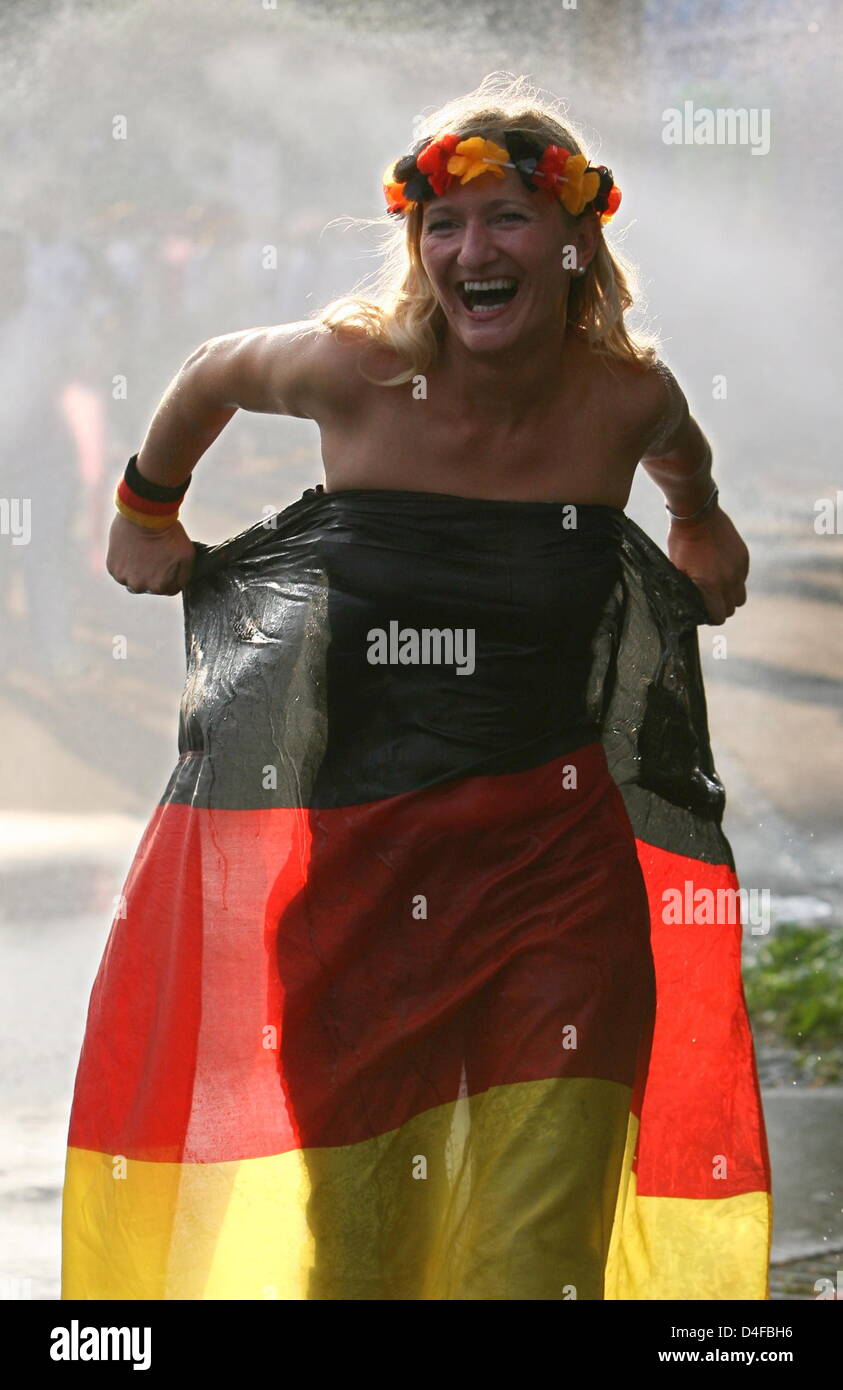 A female German supporter enjoys cooling water spraying from a water hose downtown Basel prior to the UEFA EURO 2008 semifinal match between Germany and Turkey at the St. Jakob-Park stadium in Basel, Switzerland, 25 June 2008. Photo: Oliver Berg dpa +++(c) dpa - Bildfunk+++ Stock Photo