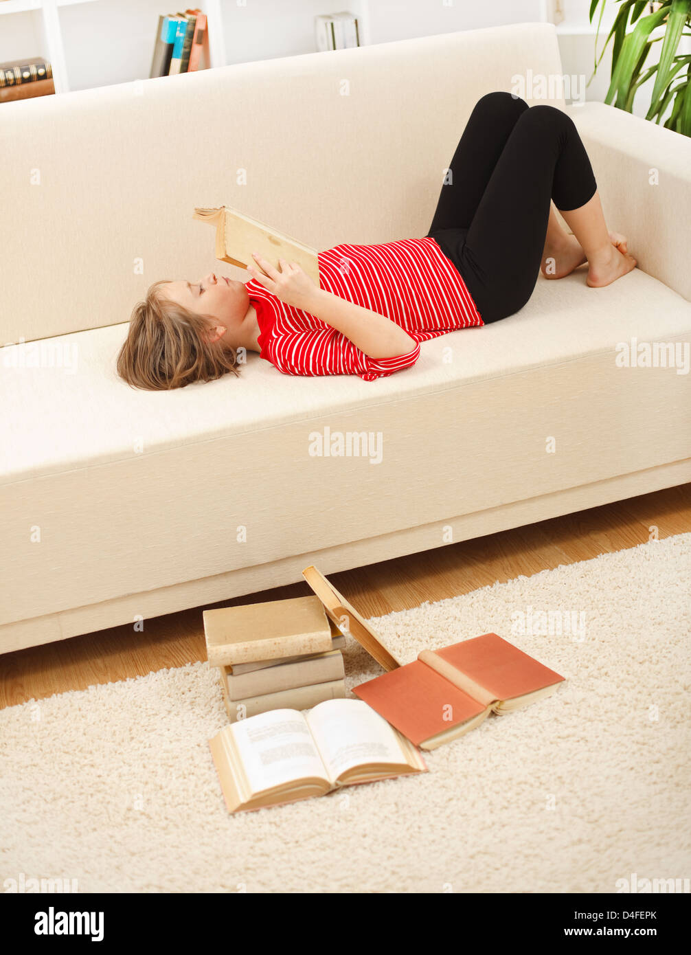 Teenager girl laying on sofa and reading books in living room Stock ...