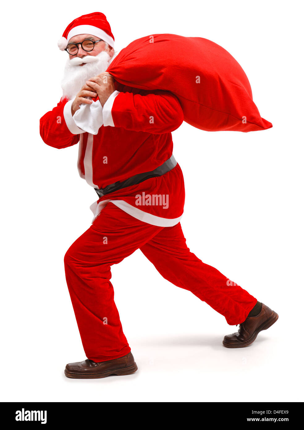 Senior man wearing Santa Claus uniform, walking with full bag Stock Photo