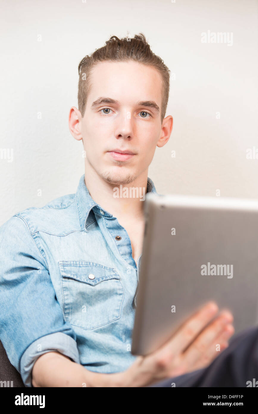 Lifestyle moment with a relaxed young adult male holding a digital tablet device in his hands. Stock Photo