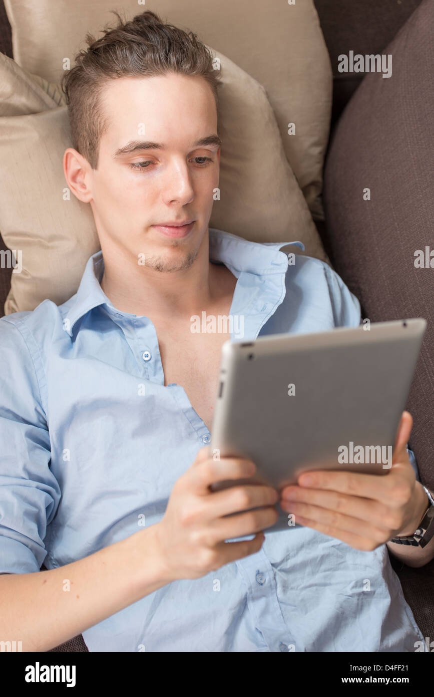 Lifestyle moment with a relaxed young adult male holding a digital tablet device in his hands. Stock Photo