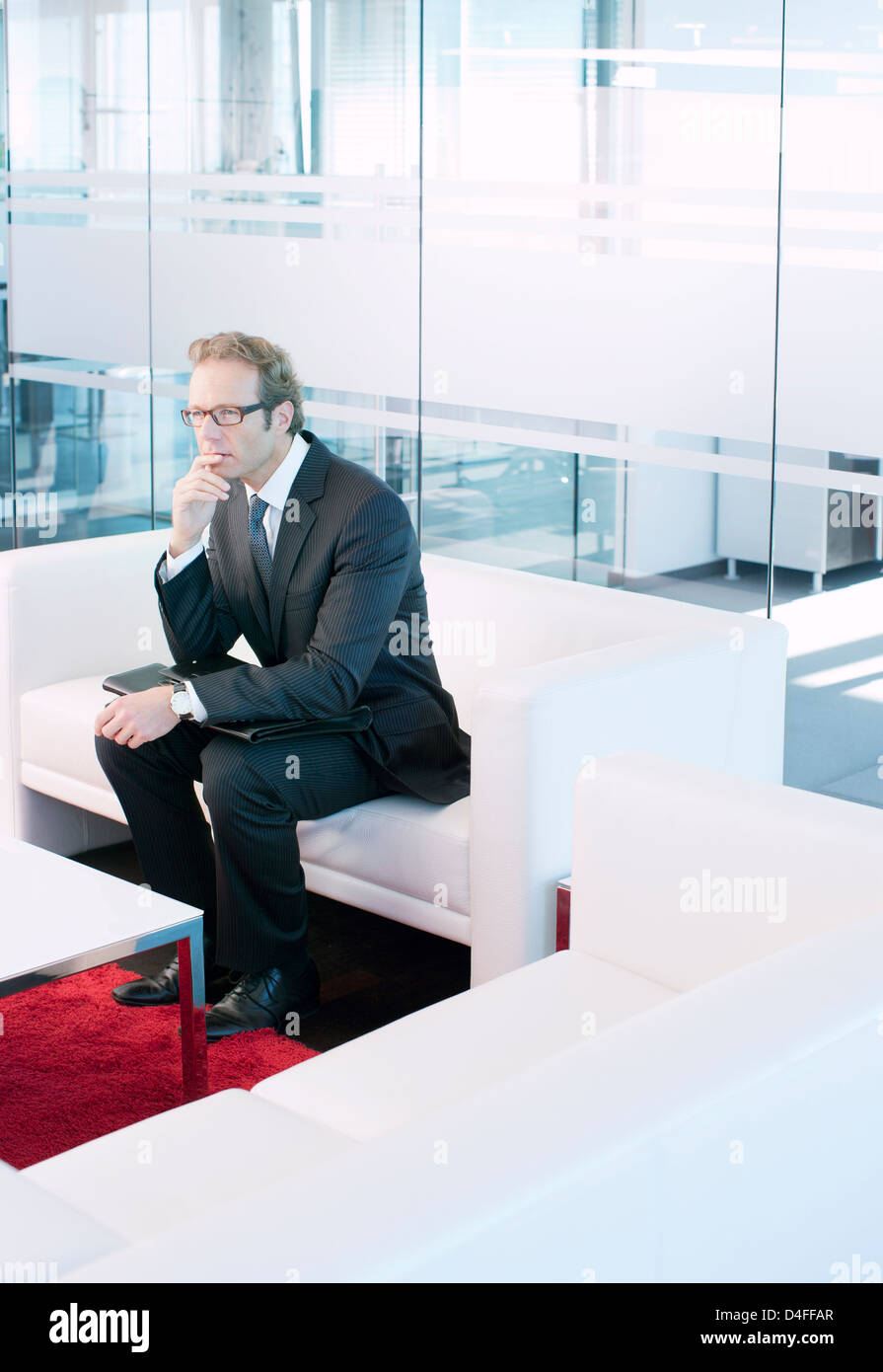 Business man sitting on sofa in office lobby Stock Photo