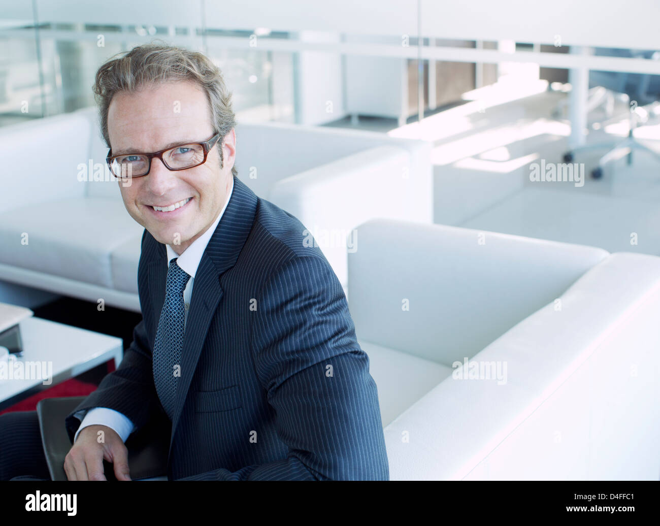 Businessman smiling in office lobby Stock Photo - Alamy