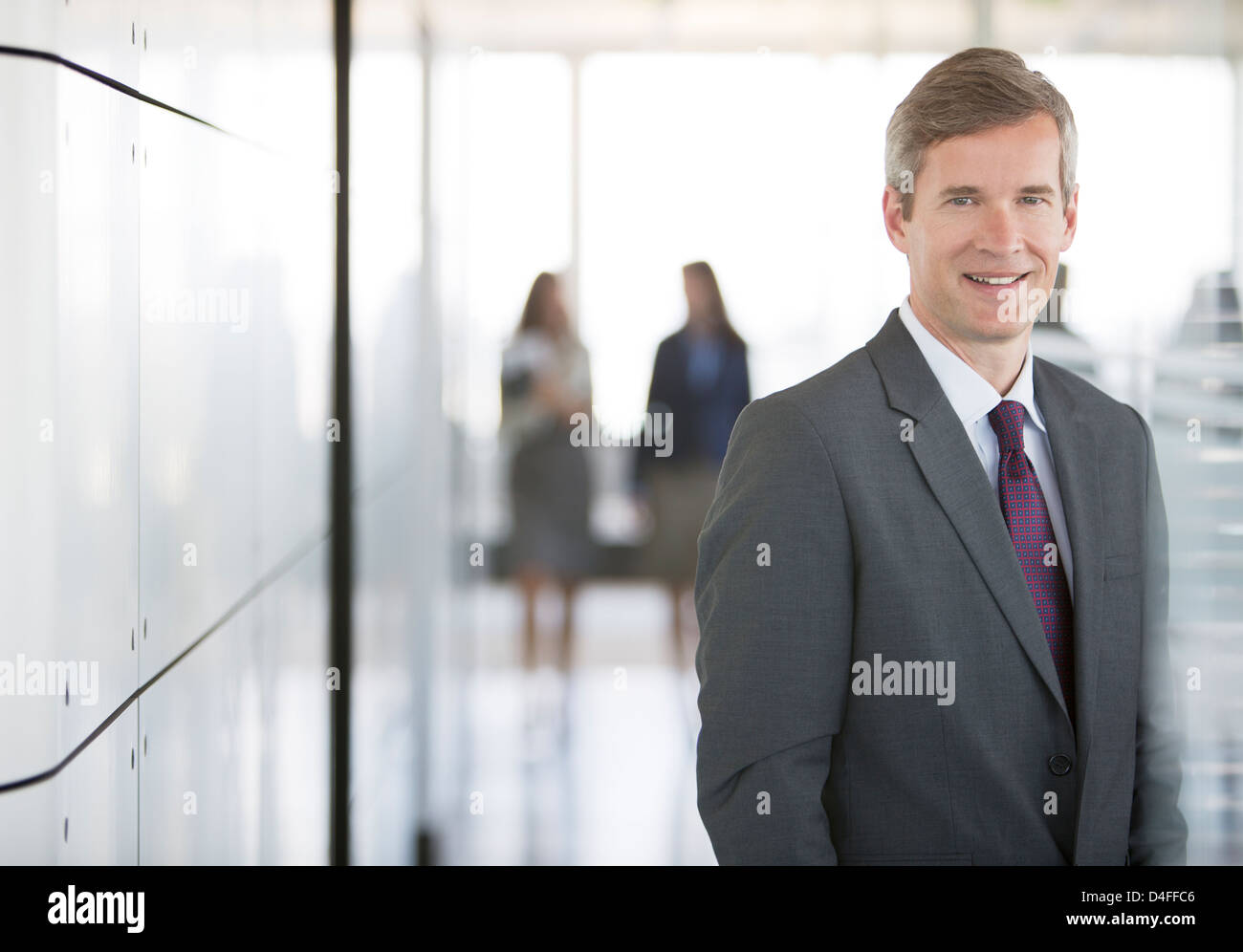 Businessman smiling in office hallway Stock Photo - Alamy