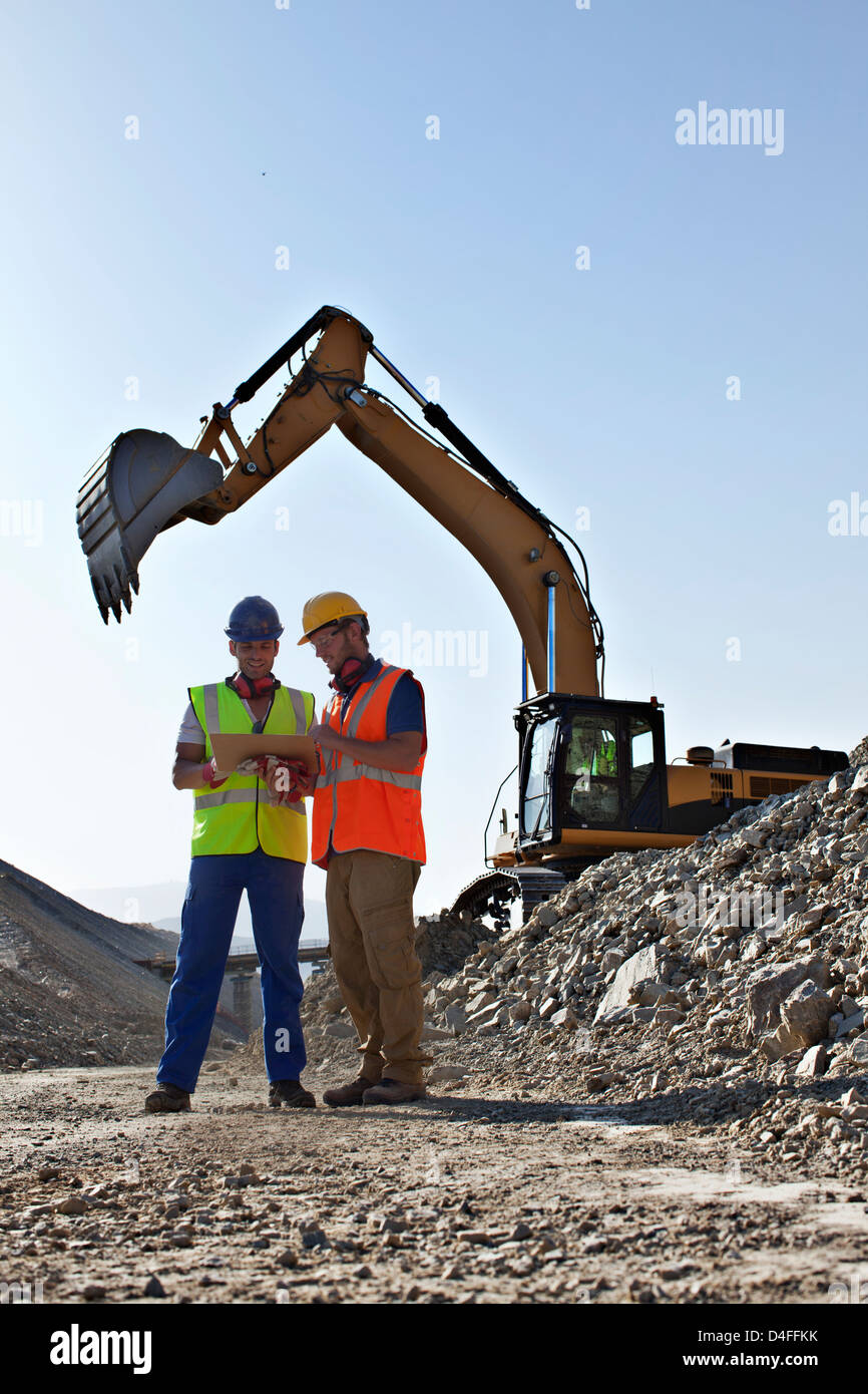 Workers talking by digger in quarry Stock Photo