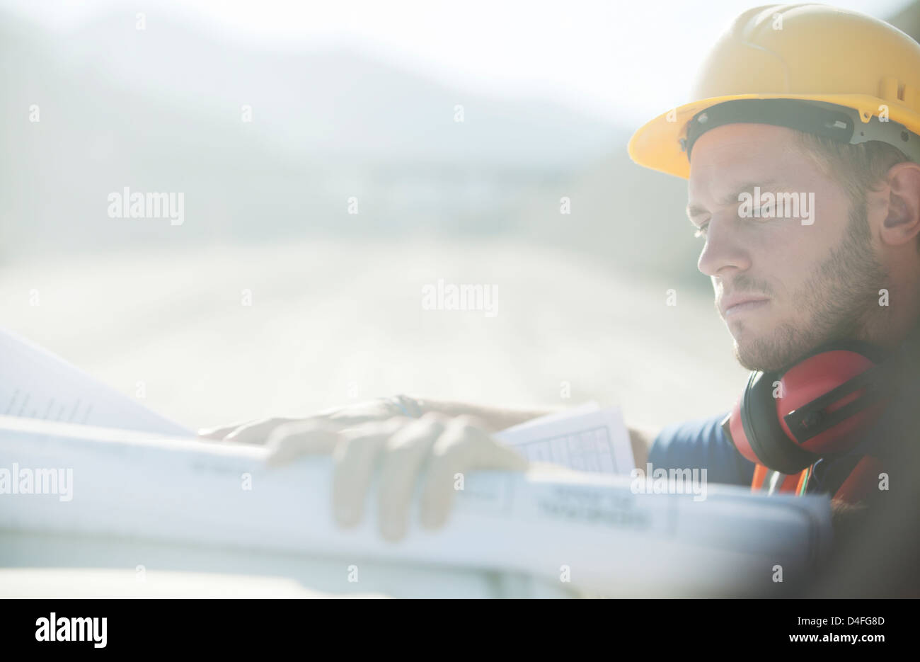 Worker reading blueprints on site Stock Photo
