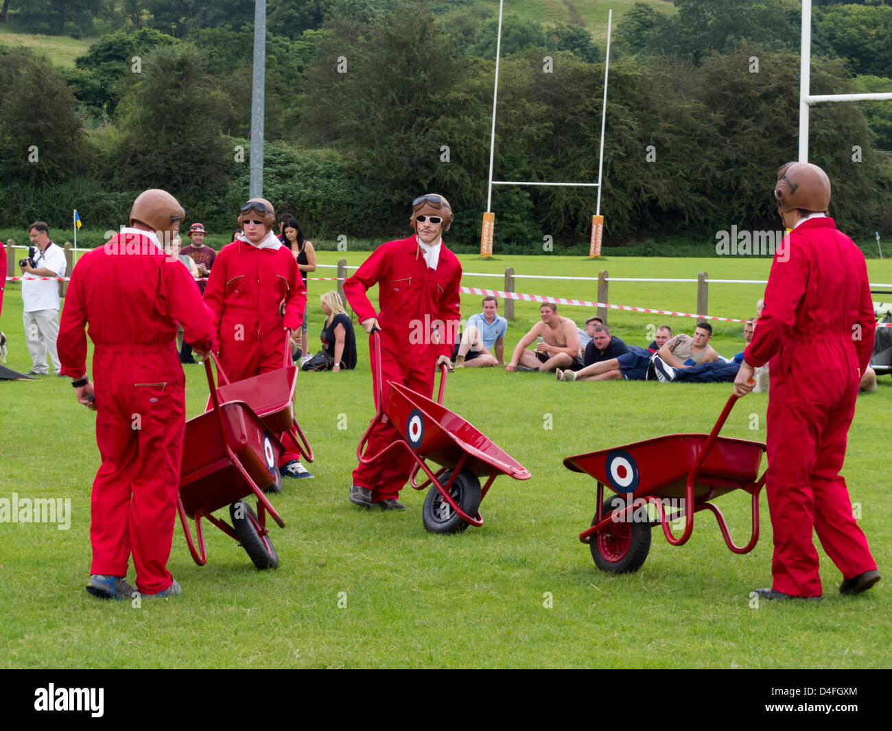 group of men wearing red boiler suits pushing red wheelbarrows round a