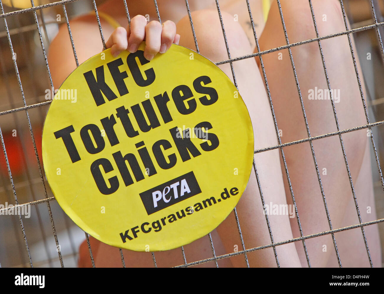 Animal rights activists of PETA sit in a cage holding signs reading 'KFC tortures chicks' across a branch of fast food chain Kentucky Fried Chicken (KFC) in Frankfurt Main, Germany, 06 August 2008. The activists aim to call attention to the fate of some 800 million chicks handled by KFC. Photo: UWE ANSPACH Stock Photo