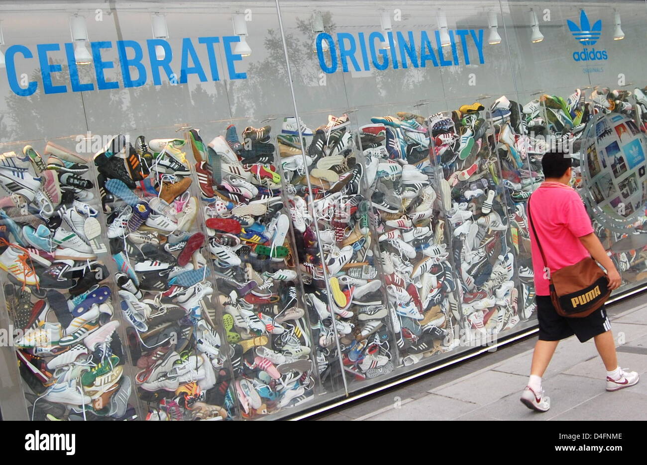 A man walks past the world's largest 'Adidas-Store' reading 'Celebrate  Originality' in Beijing, China, 13 August 2008. 'Yashow-Market' where adidas  phonies (and of other known brands) can be bought for a fraction