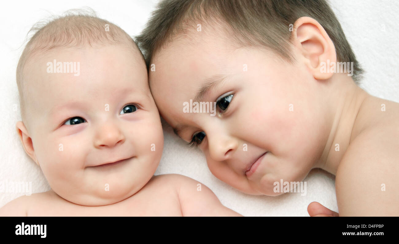 Two happy siblings together on white blanket Stock Photo