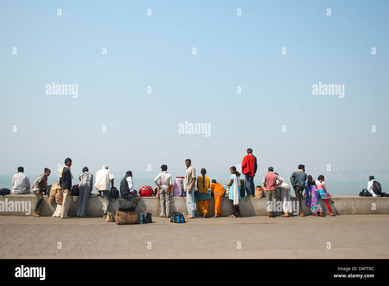 Indian tourists in Mumbai look out over Chowpatti beach all dressed in different colours Stock Photo