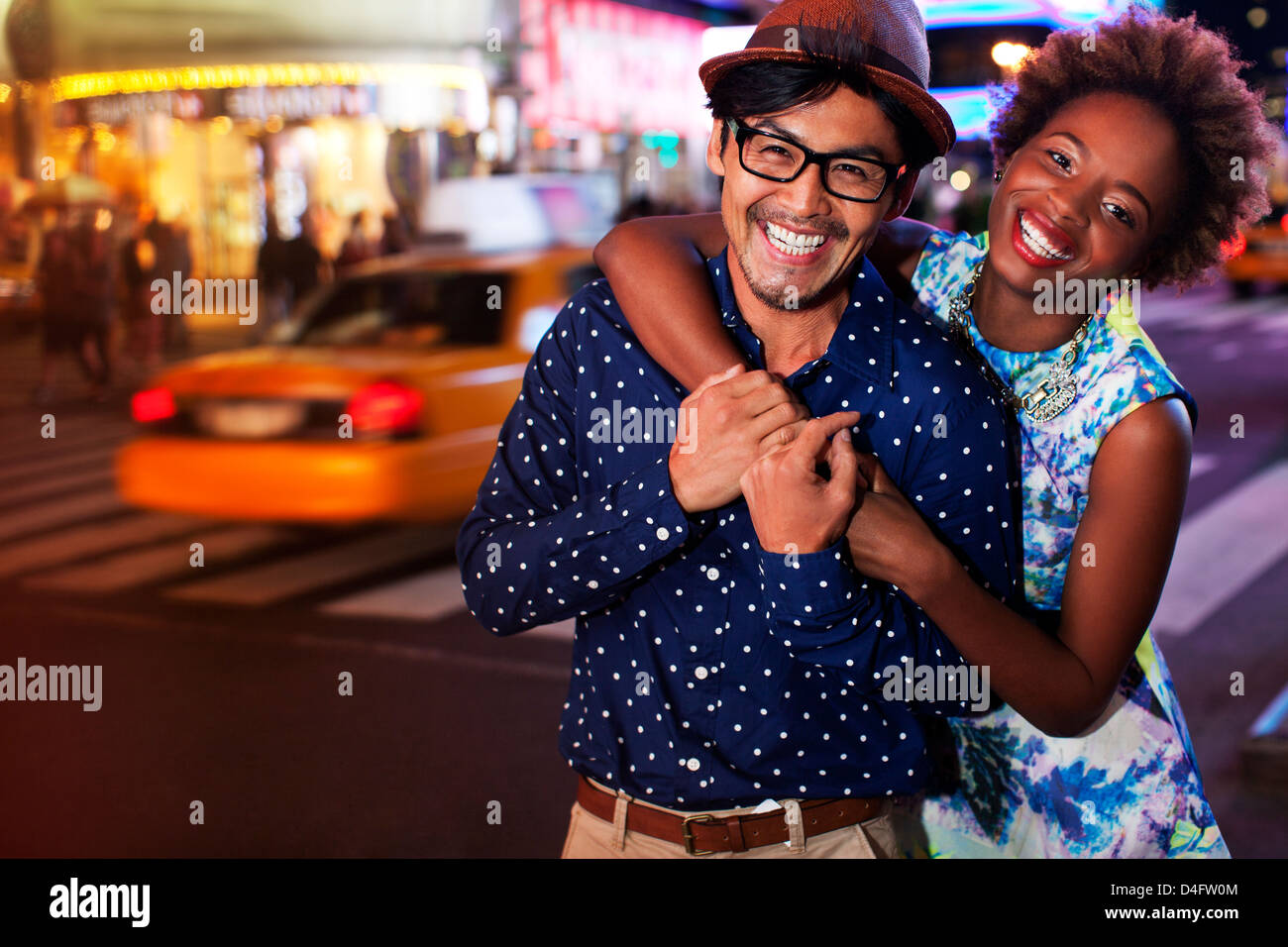 Couple smiling on city street at night Stock Photo