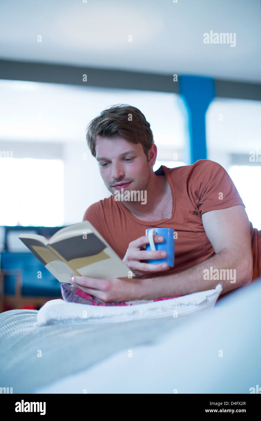 Man reading book on bed Stock Photo