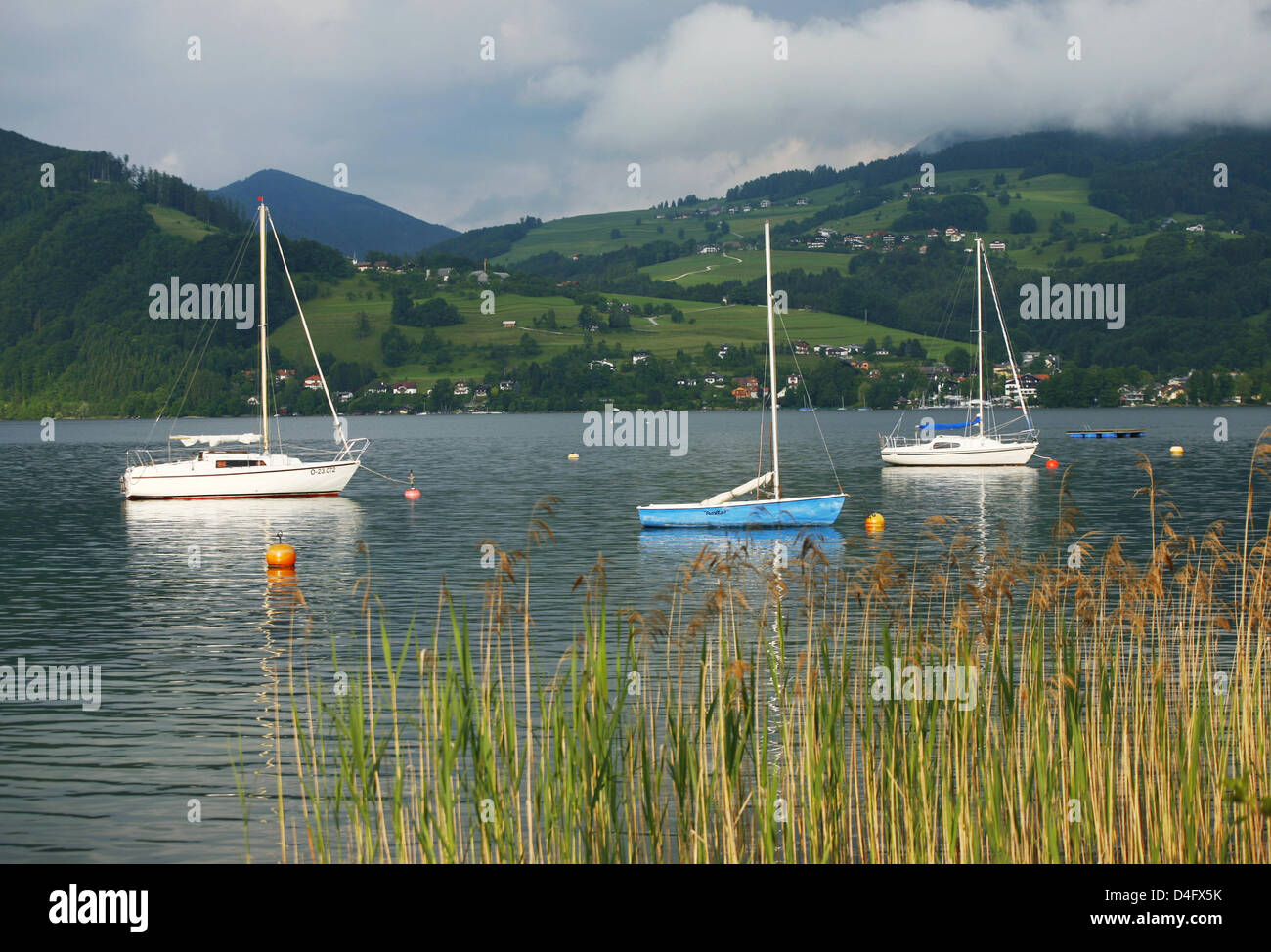 Under an overclouded sky, sailing boats lie calmly on the water of the Attersee near Aich, Austria, June 2008. Photo: Wolfram Steinberg Stock Photo