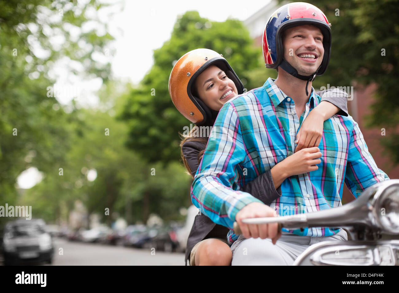 Couple riding scooter together outdoors Stock Photo