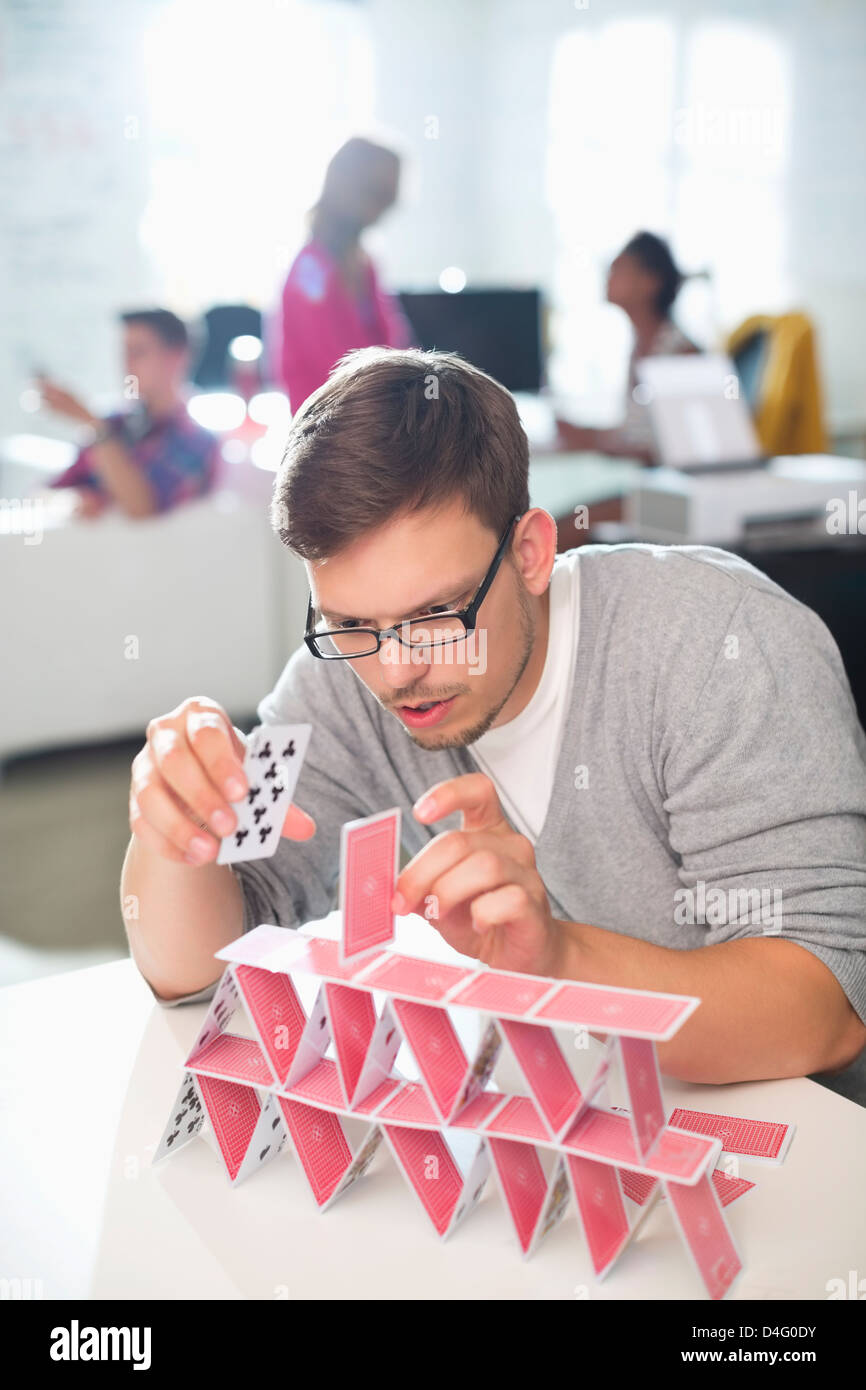 Businessman making house of cards in office Stock Photo