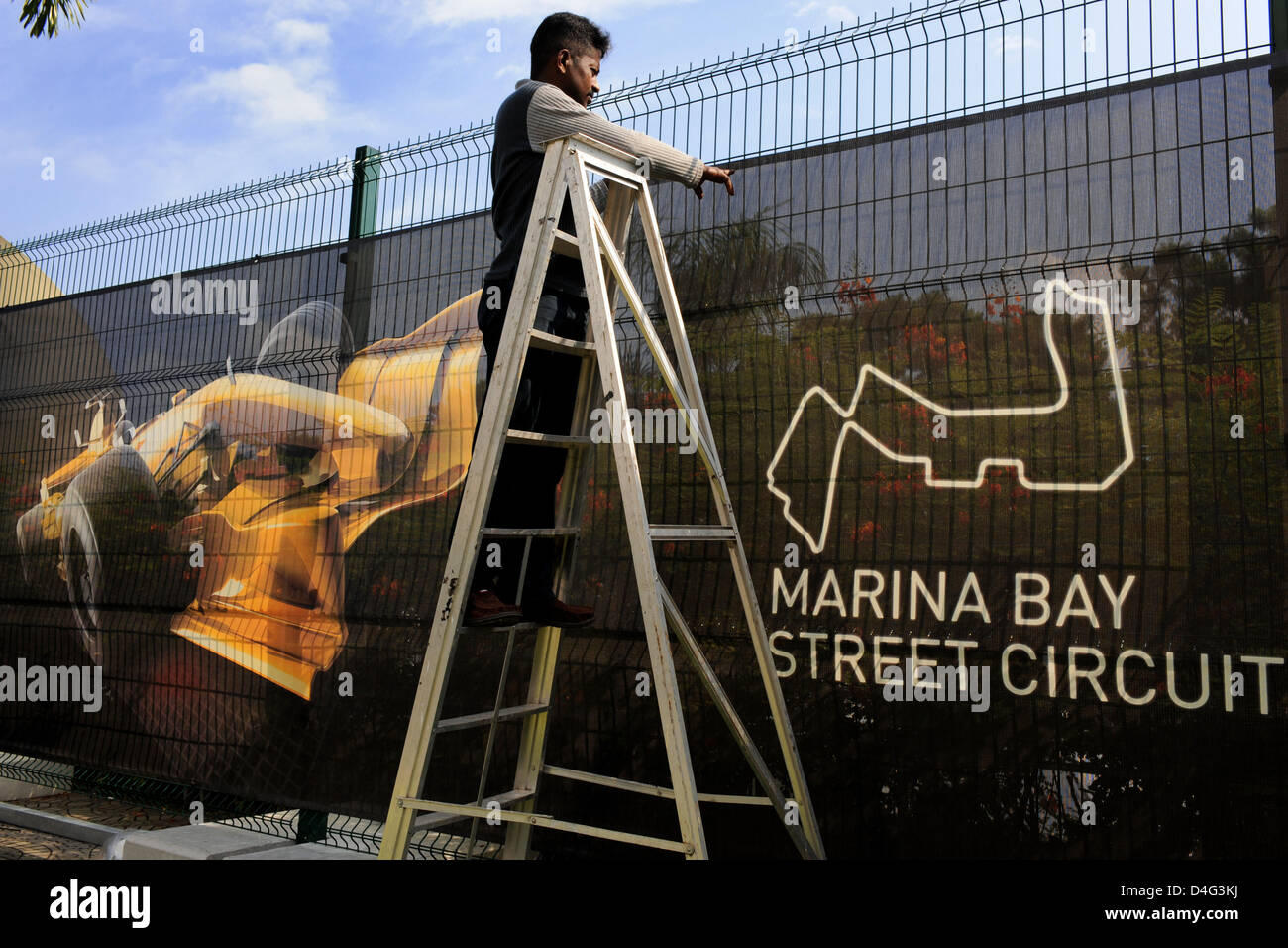 A Man Attaches An Advertising Banner To A Fence For The Formula 1