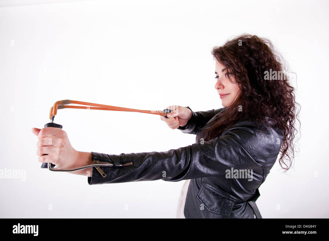 brunette young girl holding a slingshot aiming on the left side Stock Photo