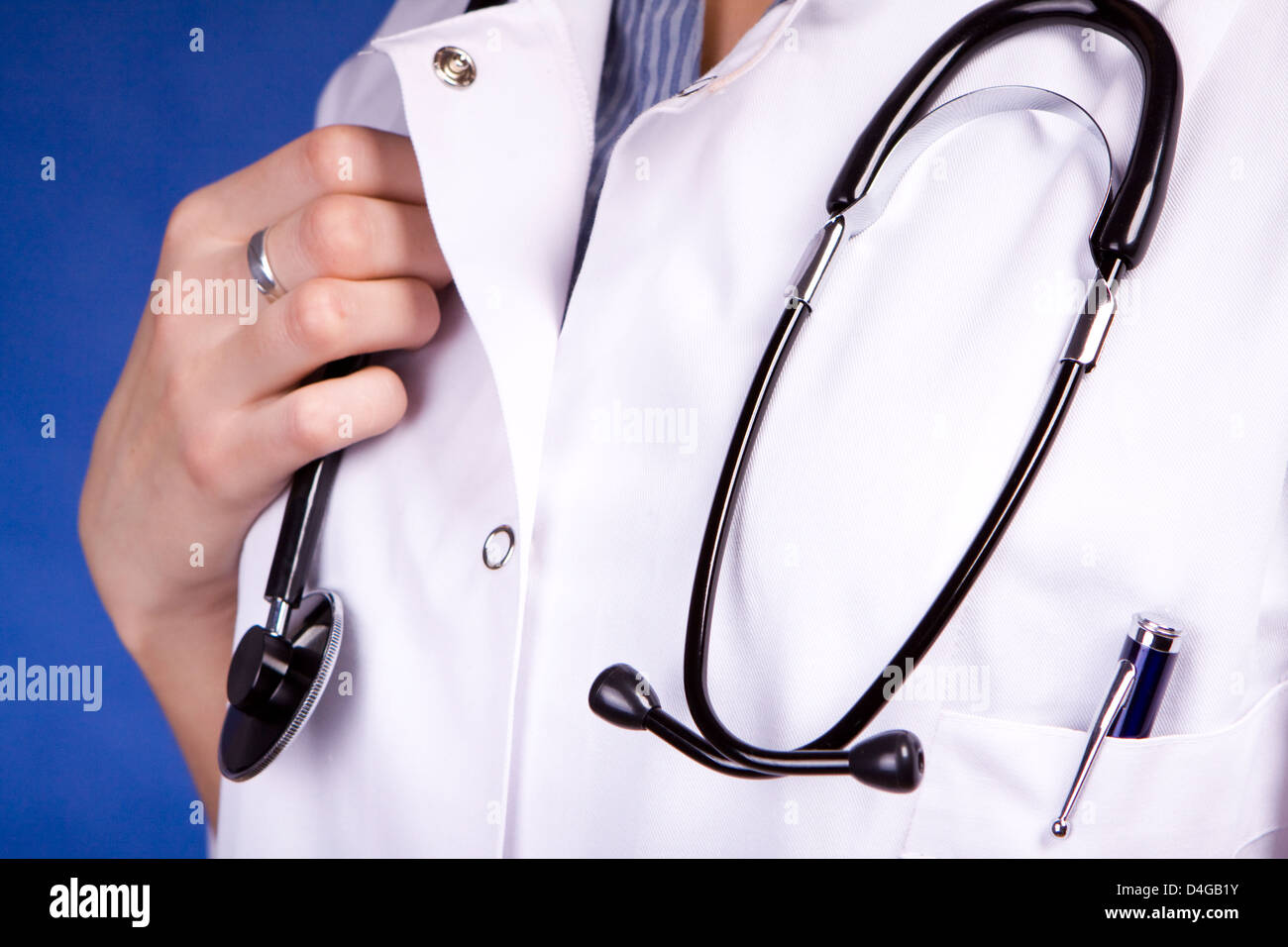 Nurse or doctor holding stethoscope in white scrubs Stock Photo