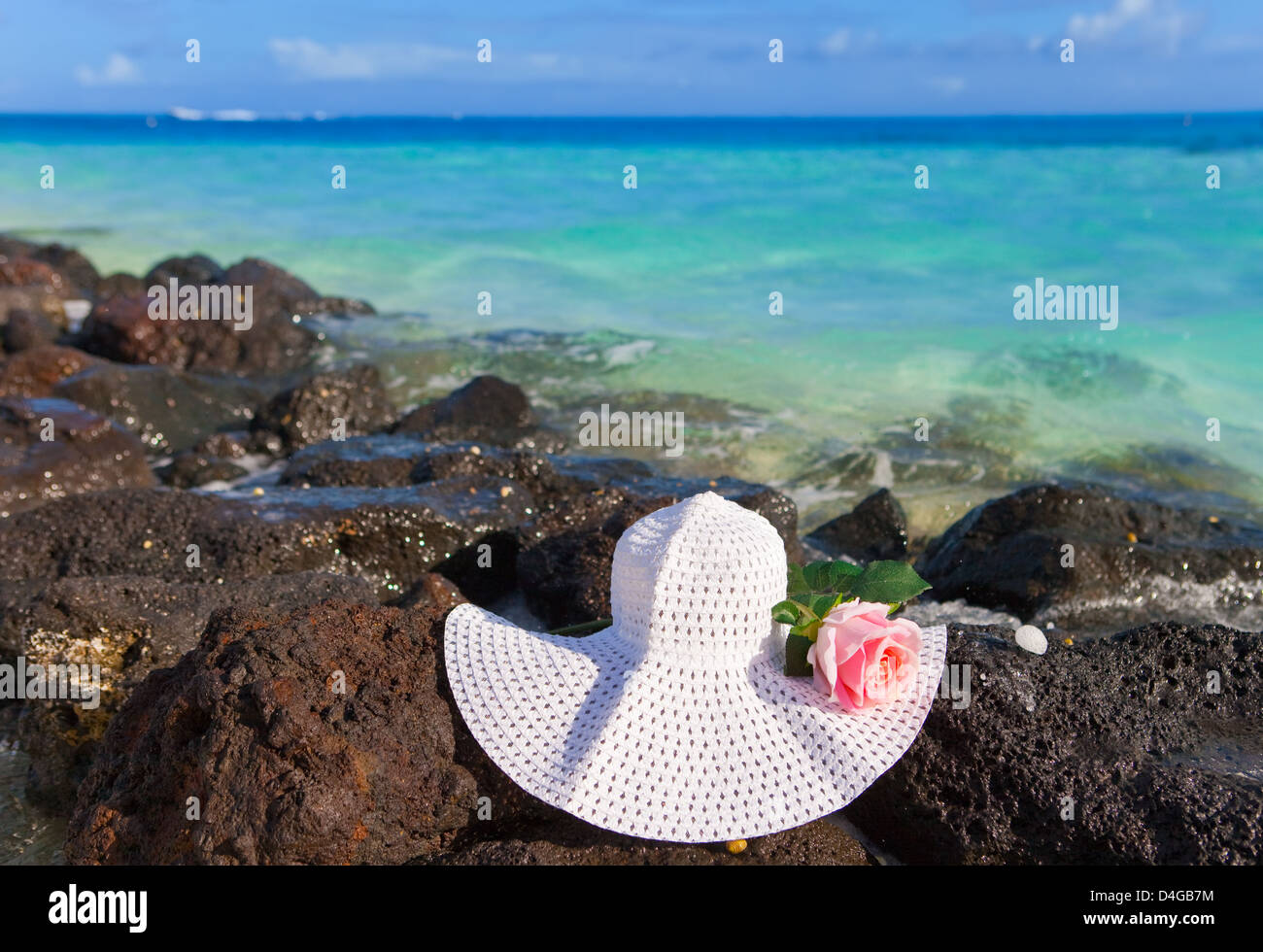 The rose and straw hat lies on stones on the sea background Stock Photo ...