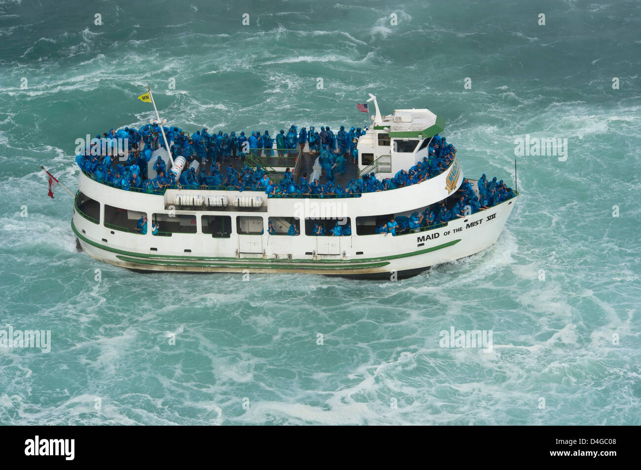 Maid of the Mist boat carrying tourists at the bottom of Niagara Falls ...