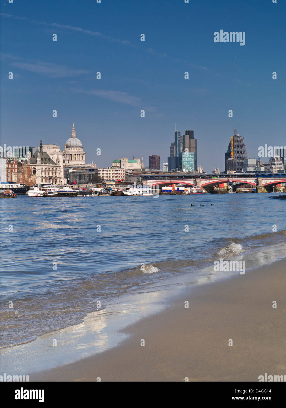 City of London and Saint Paul's with calm River Thames at low tide revealing clean warm sandbank in foreground London UK Stock Photo