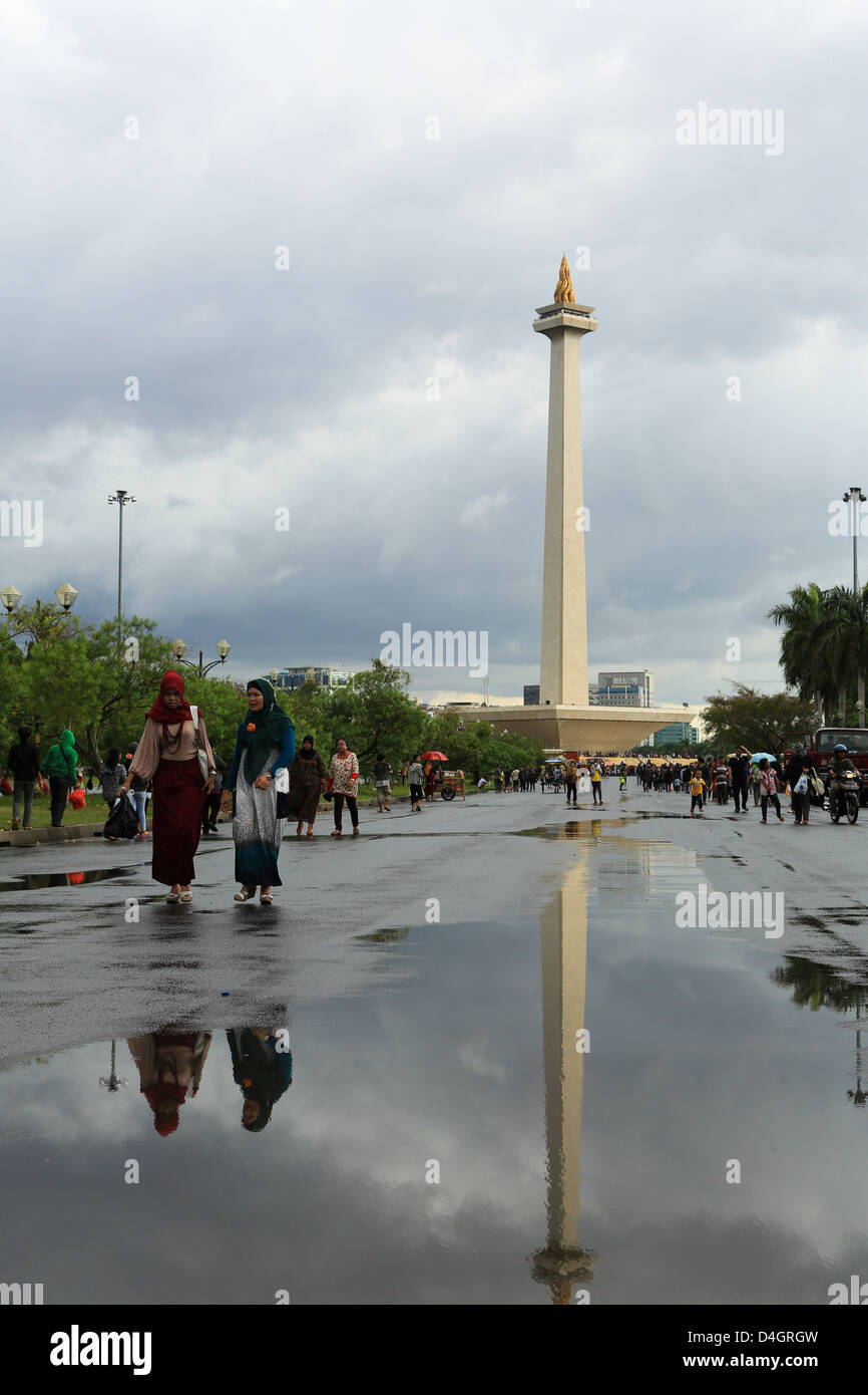 Two muslim women walking in front of  the Monas (monument national) on a rainy day in Jakarta, Indonesia Stock Photo