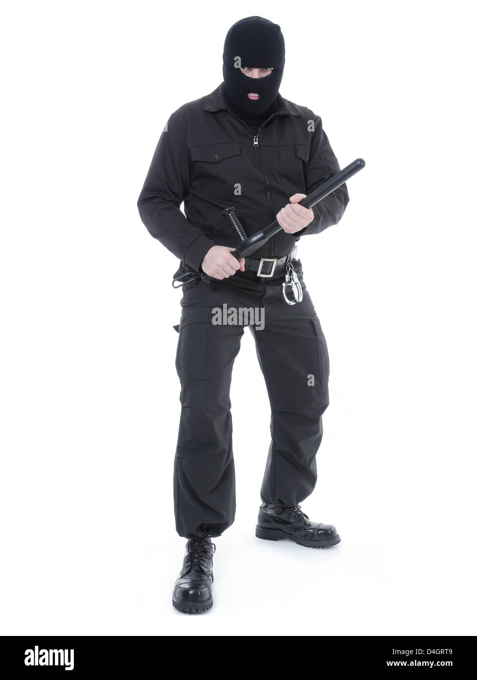 Antiterrorist police guy wearing black uniform and black mask holding firmly police club in both hands ready for action Stock Photo