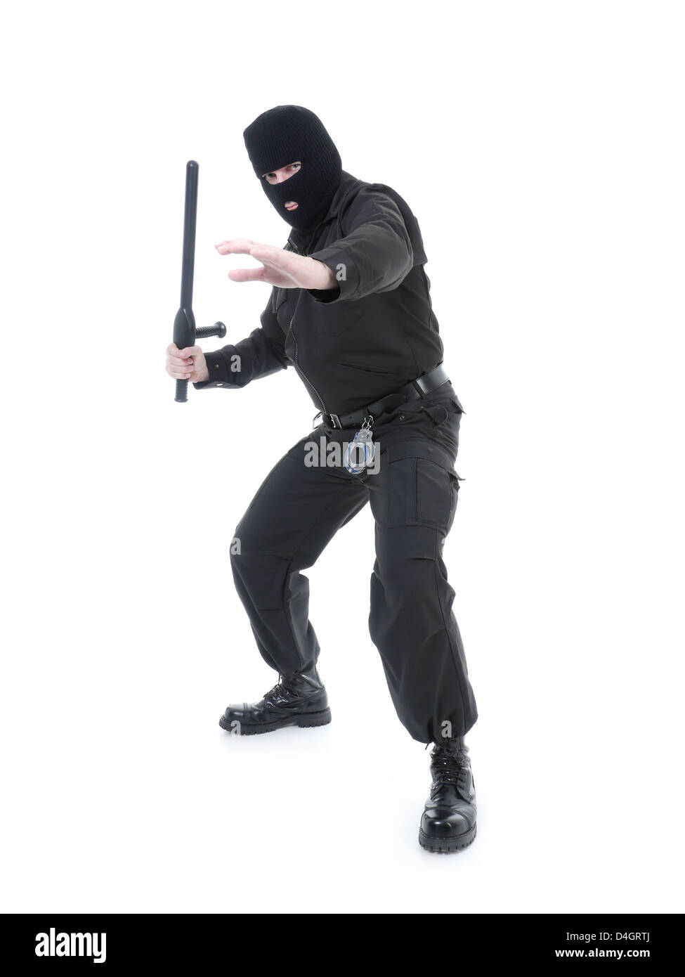 Anti-terrorist police guy wearing black uniform and black mask holding firmly police club in one hand Stock Photo