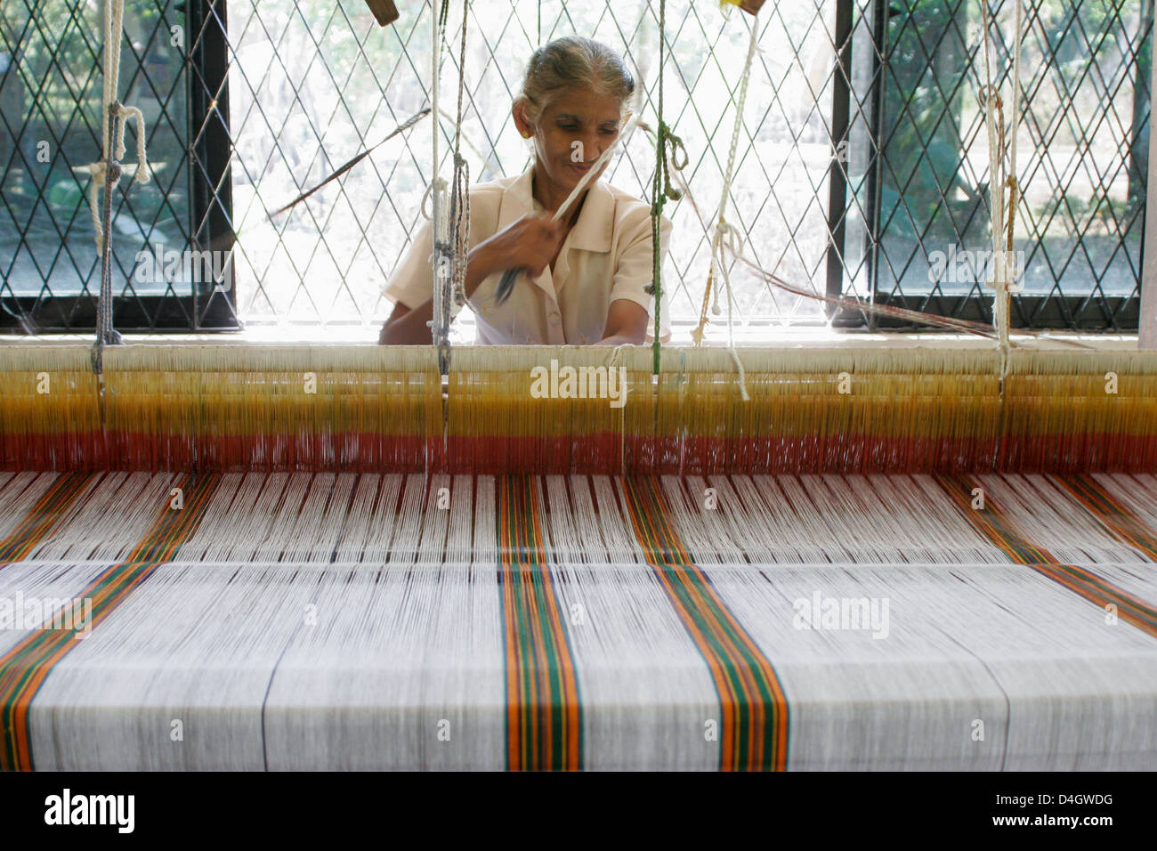 A woman working at a loom weaving textile, Beruwala, Sri Lanka Stock Photo