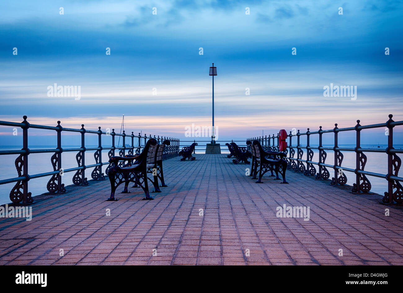 Summer sunrise and empty benches ot the Banjo Pier at Swanage in Dorset Stock Photo
