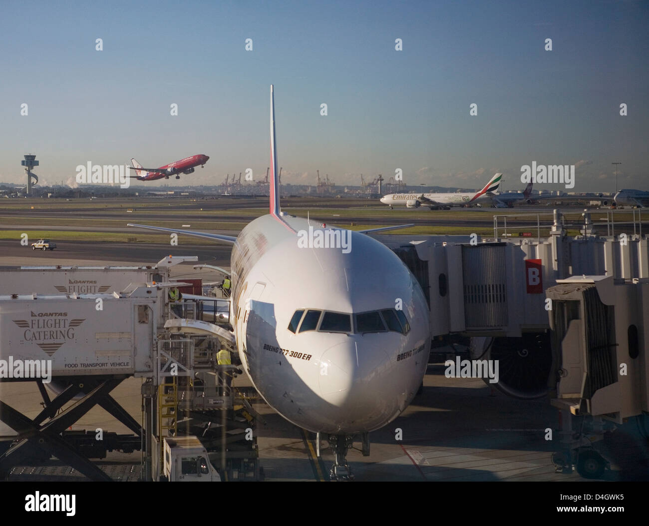 Boeing 777-300 ER jet airliner of Emirates Airline at gate, Emirates and Virgin Blue planes behind, Sydney Airport, Australia Stock Photo