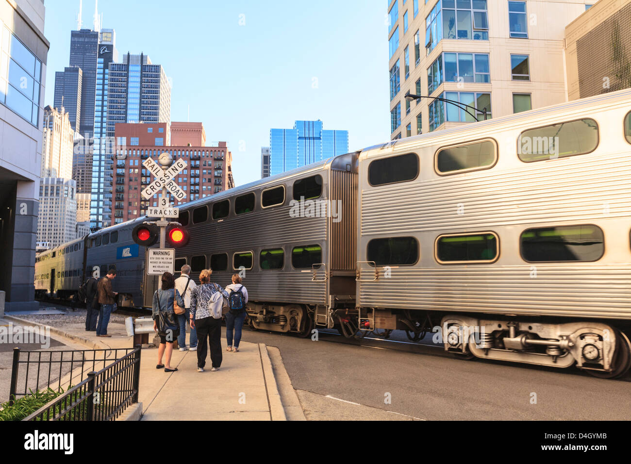 Metra Train passing pedestrians at an open railroad crossing, Downtown, Chicago, Illinois, USA Stock Photo