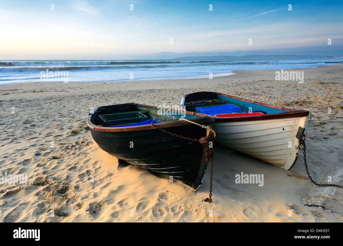 Fishing boats on a sandy beach in Bournemouth with Old harry rocks and the Isle of Purbeck in