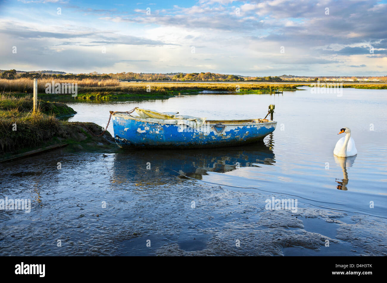 Old blue boat moored in salt marshes in the backwaters of Poole Harbour in Dorset Stock Photo