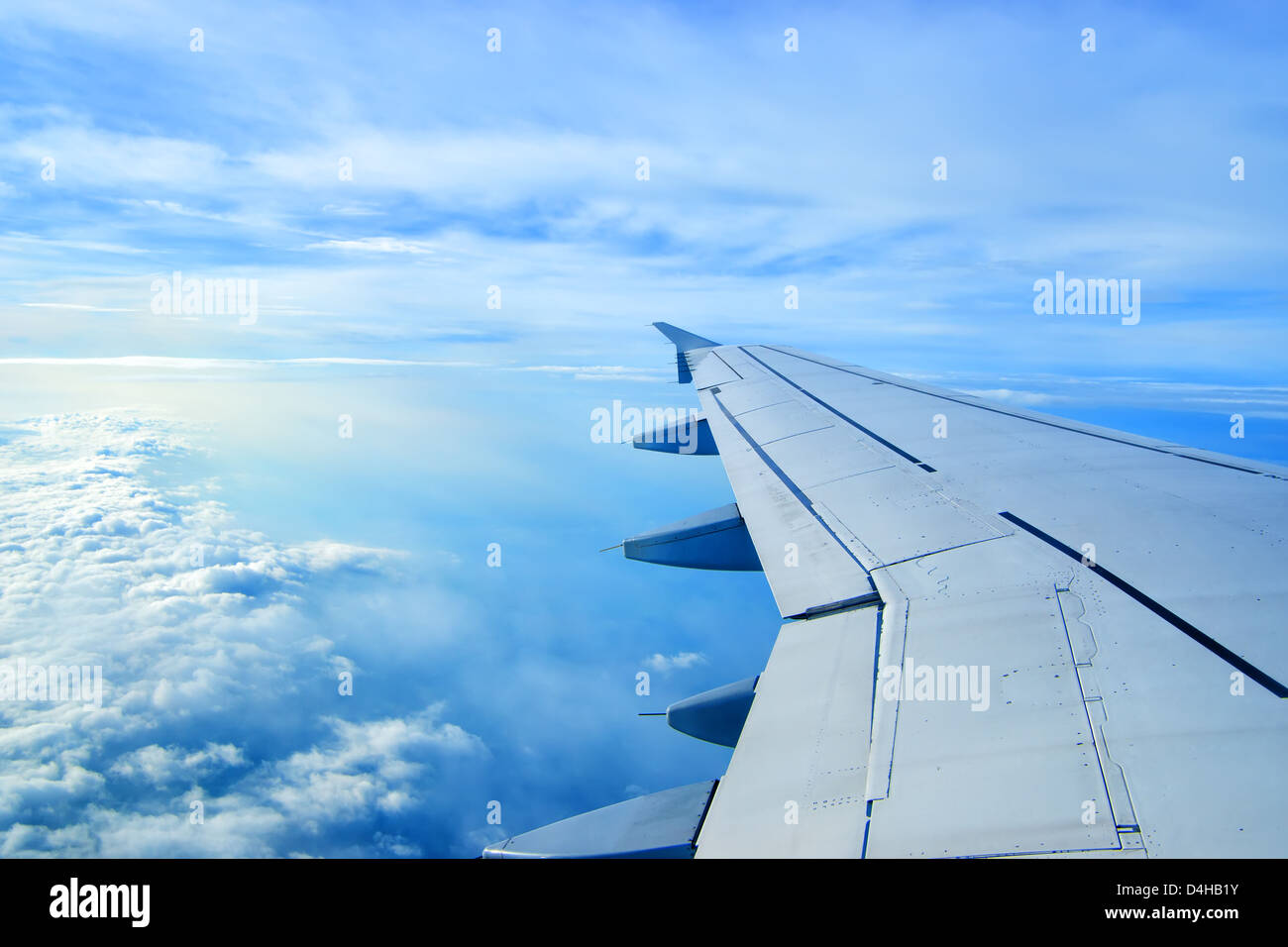 Wing of an airplane flying above the clouds. people looks at the sky from the window of the plane, using airtransport to travel. Stock Photo