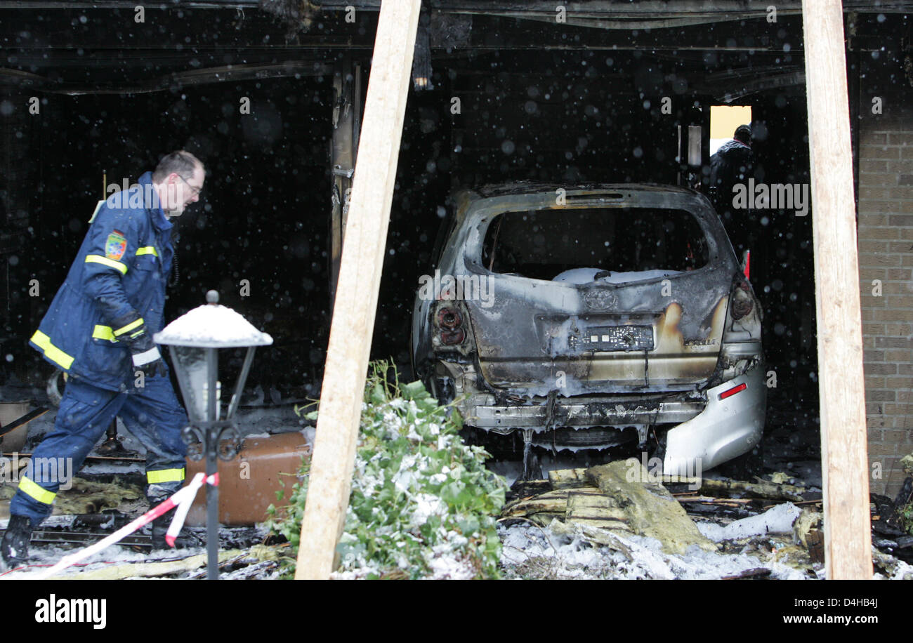 An assistant of THW (German Federal Agency for Technical Relief) passes a burnt out car in Osnabrueck, Germany, 22 November 2008. A 32-year-old woman and her 53-year-old mother died in the accident in the morning of 22 November. As the police reported, the woman?s 33-year-old husband crashed with his car into the house of his parents-in-law causing a fire. The woman?s 66-year-old f Stock Photo