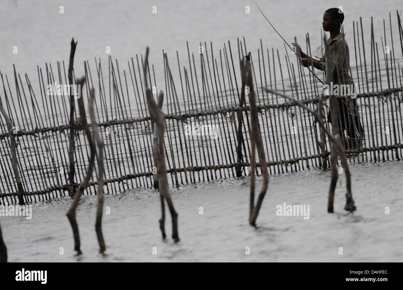 A young fisherman with a primitive fishing rod stands on the Kosi